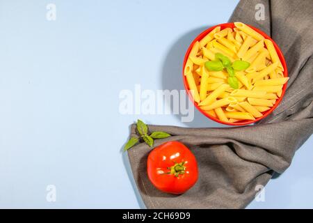 Pasta e ingredienti per cucinare su sfondo blu, vista dall'alto. Concetto di cucina italiana. Pasta, pomodori, basilico, verdure. Spazio di copia Foto Stock