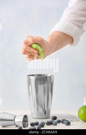 Donna che fa gustoso mojito cocktail a tavola Foto Stock