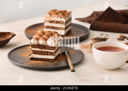 Piatti con gustoso tiramisù e tè sul tavolo Foto Stock