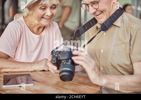 Coppia anziana moderna e allegra seduta in un caffè Foto Stock