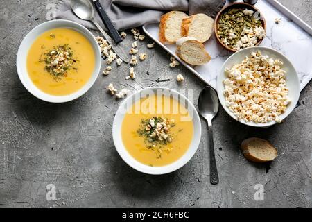 Ciotole con gustosa zuppa di popcorn su sfondo grigio Foto Stock