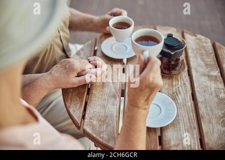 La coppia anziana beve il tè ad un tavolo di legno all'aperto Foto Stock