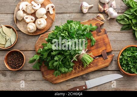 Tavola con prezzemolo fresco, funghi e spezie su sfondo di legno Foto Stock