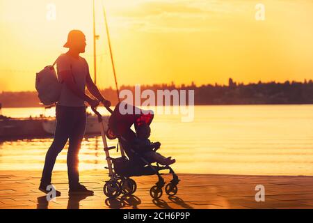 L'uomo e il suo bambino carino in passeggino vicino al fiume Foto Stock