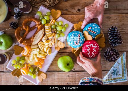 Vista dall'alto delle ciambelle invernali della vigilia di natale decorazioni - le persone che mangiano cibo dolce e godono festa celebrazione - tavolo in legno Foto Stock