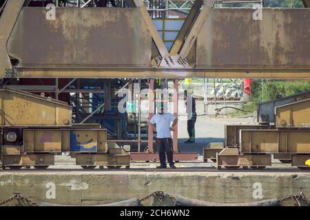 Gdansk, Polonia del Nord - 14 agosto 2020: Un operaio industriale in uniforme che lavora in un cantiere vicino al fiume motlawa durante la pandemia della corona in estate t Foto Stock