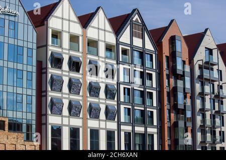 Gdansk, Polonia del Nord - 14 agosto 2020: Primo piano di un gruppo di diversi esterni colorati dell'edificio con il fiume mottawa riflesso sulla sua finestra Foto Stock