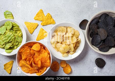 Diversi tipi di patatine in ciotole bianche, fondo grigio. Concetto di fast food. Foto Stock