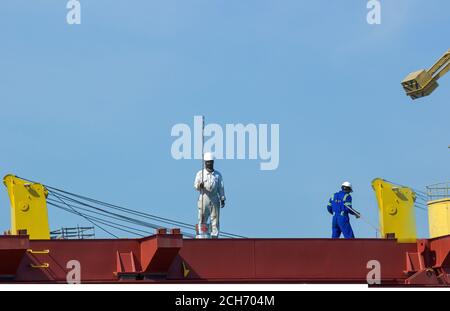 Gdansk, Polonia del Nord - 14 agosto 2020: Coppia di lavoratori industriali in uniforme che lavorano in un cantiere navale vicino al fiume motlawa durante la pandemia di corona in s. Foto Stock