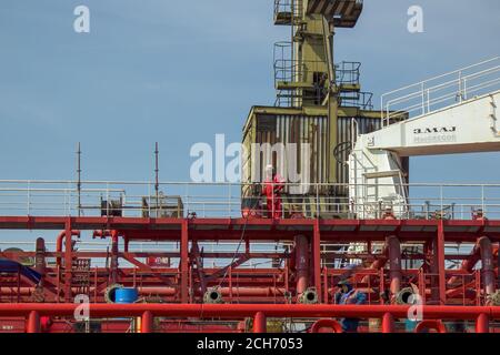 Gdansk, Polonia del Nord - 14 agosto 2020: Un operaio industriale in uniforme che lavora sopra il cantiere navale laterale del fiume motlawa in estate Foto Stock