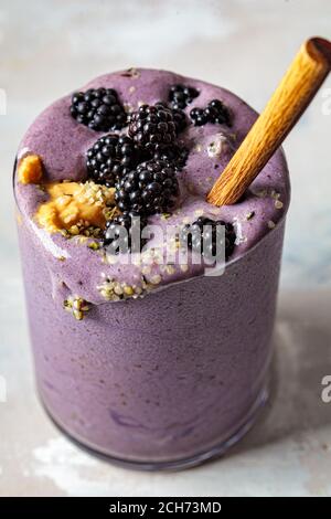 Frullato di Berry con burro di arachidi e semi di canapa in un bicchiere. Concetto di cibo vegano sano. Foto Stock