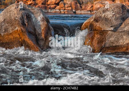 Fiume tempestoso rotola su pietre Foto Stock