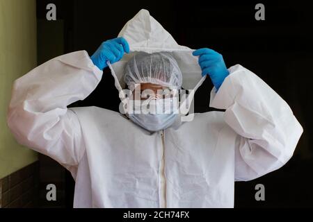Medico che indossa tuta ppe, maschera chirurgica facciale e visiera che combatte contro l'esplosione del virus corona Foto Stock