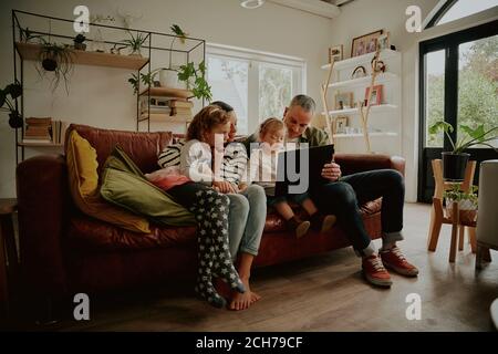 Giovane famiglia con figlia che guarda i video sul computer portatile mentre si rilassa a casa Foto Stock