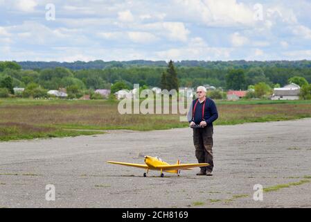 Un uomo anziano lancia un aereo radiocontrollato sulla pista in primavera. Foto Stock