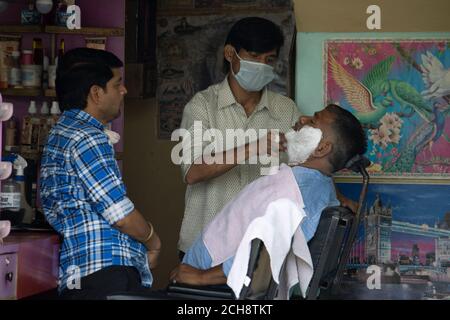 Dehradun, Uttarakhand/India - Settembre 08 2020:Salon proprietario rasatura di un uomo che indossa una maschera facciale. Foto Stock