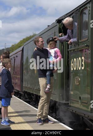 Il pompiere Gordon Hodgson, 77 anni, di Carlisle, parla con John Gow, 37 anni, da Turnside e sua figlia Darcy, 5, mentre Flying Scotsman arriva alla stazione ferroviaria di Tweedbank dalla stazione di Waverley a Edimburgo a Tweedbank ai confini, Mentre continua il suo tour in Gran Bretagna dopo che Network Rail ha invertito la decisione di annullare i viaggi con breve preavviso. Foto Stock