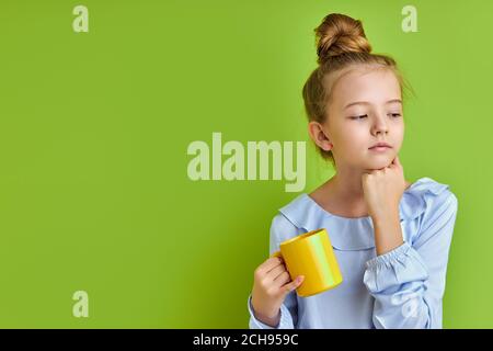 sonnolenta bambina non ha abbastanza sonno la mattina prima di scuola, lei sta tenendo una tazza di caffè, stanca Foto Stock