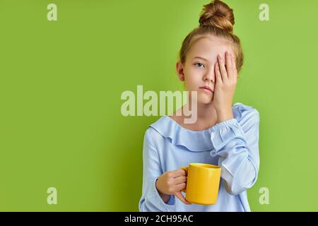 sonnolenta bambina non ha abbastanza sonno la mattina prima di scuola, lei sta tenendo una tazza di caffè, stanca Foto Stock