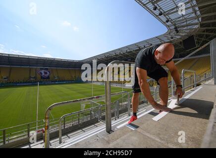 Dresda, Germania. 11 Settembre 2020. Un freelance della squadra di calcio di terza divisione SG Dynamo Dresden collana le marcature per le distanze sui gradini del K-Block al Rudolf-Harbig-Stadium. Il 14 settembre 2020, il club gioca contro Hamburger SV davanti agli spettatori nel primo round della Coppa DFB. Credit: Robert Michael/dpa-Zentralbild/dpa/Alamy Live News Foto Stock