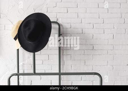 Cappello bianco e nero sull'appendiabiti. Muro di mattoni bianchi Foto Stock