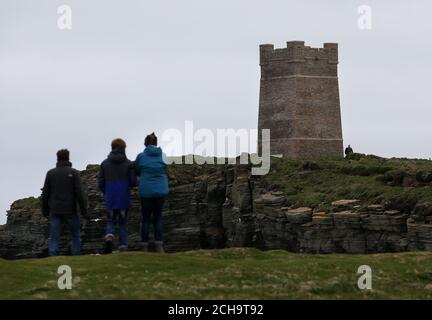 I visitatori camminano lungo le cime delle scogliere alte sopra il mare a Marwick Head in Orkney, dove si erge la torre costruita per onorare la memoria di Lord Kitchener. Foto Stock