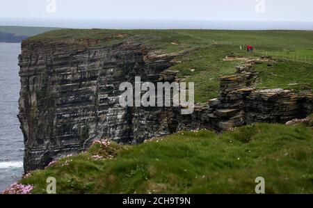 I visitatori camminano lungo le cime delle scogliere alte sopra il mare A Marwick Head in Orkney