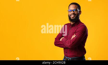 Sorridente afro uomo che posa su sfondo giallo Foto Stock