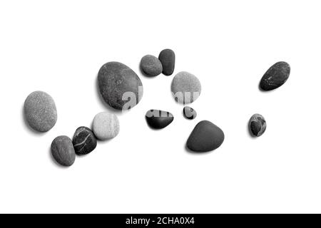 Ciottoli di mare sparsi. Pietre nere e grigie lisce isolate su sfondo bianco. Vista dall'alto Foto Stock