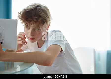 teen guarda la sua pelle di faccia di problema nello specchio, vuole liberarsi di acne. a casa Foto Stock