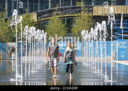 Birmingham West Midlands, 14 settembre 2020. Un paio di cammina a piedi nudi attraverso le fontane di Centenary Square, Birmingham, godendosi il caldo sole mattutino in quello che si prevede sia il giorno più caldo del mese. La maggior parte delle persone osservava la "regola dei 6", tuttavia un gruppo di anziani superava 8 persone mentre veniva mostrato il municipio della città in Victoria Square. Birmingham si sta preparando ad andare in un blocco locale martedì a causa di un picco di casi di coronavirus. La città vieterà alle persone di entrare in altre famiglie a meno che non sia esente. Credito: Interrompi stampa Media/Alamy Live News Foto Stock