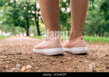 Pareggiatore femminile che si prepara a correre lungo il percorso nel parco, primo piano di gambe e scarpe con fuoco selettivo Foto Stock