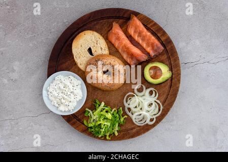 Bagel di salmone con ingredienti disposti su un tavolo di legno Foto Stock