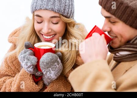 Bevanda calda. Una coppia romantica che beve cioccolata calda all'aperto durante il giorno d'inverno Foto Stock