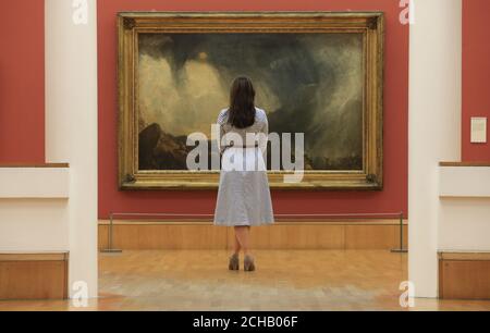 Una donna guarda l'opera di JMW Turner Snow Storm: Hannibal e la sua Armata Crossing the Alps 1812, uno dei dipinti che sono tornati a Tate Britain a Londra dopo un importante tour internazionale. Foto Stock