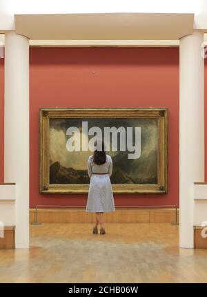 Una donna guarda l'opera di JMW Turner Snow Storm: Hannibal e la sua Armata Crossing the Alps 1812, uno dei dipinti che sono tornati a Tate Britain a Londra dopo un importante tour internazionale. Foto Stock