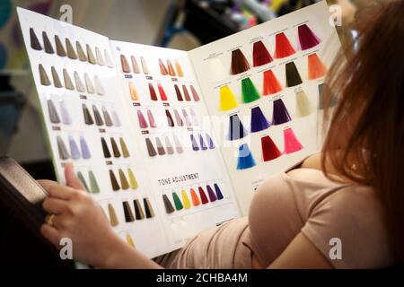 una ragazza sta osservando la tabella di colore dei capelli per la scelta nuovo colore per i suoi capelli in salone professionale Foto Stock