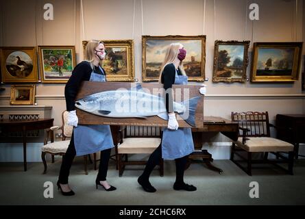 May Matthews (a sinistra) e Romy Clark da Bonhams Edinburgh portano un modello di legno intagliato di un salmone Atlantico da Rogers Brookes (stima £1,500-2,000) durante una chiamata fotografica per la vendita imminente casa e interni, e Sporting e Wildlife, a Bonhams, Edinburgh, il 23 settembre 2020. Foto Stock