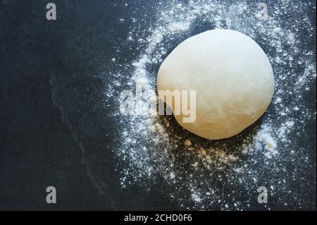 Palla di pasta per gnocchi o pasta sulla tavola di pietra. Impastare con farina, uova, sale .impasto grezzo.cottura fatta in casa. Foto Stock