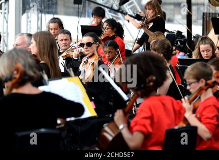 SOLO PER USO EDITORIALE Sir Simon Rpicle dirige la London Symphony Orchestra con 50 musicisti LSO sulla pista da tutta la East London e i musicisti della Guildhall School alla BMW Classics a Trafalgar Square, Londra. Foto Stock