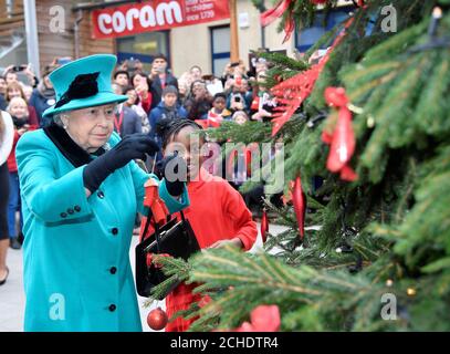 La regina Elisabetta II e Shylah Gordon, di 8 anni, attaccano un babble ad un albero di Natale durante la sua visita a Coram, la più antica associazione di beneficenza per bambini del Regno Unito, per aprire il Queen Elizabeth II Center alla sua base nel centro di Londra. Foto Stock