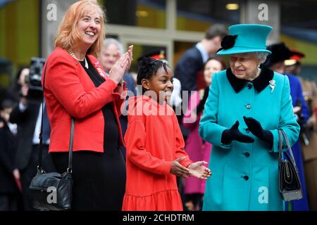 La regina Elisabetta II (a destra) con Shylah Gordon, di 8 anni, e l'amministratore delegato di Coram Carol Homden applaudono i cantanti carol durante la sua visita a Coram, la più antica associazione di beneficenza per bambini del Regno Unito, per aprire il Queen Elizabeth II Center alla sua base nel centro di Londra. Foto Stock