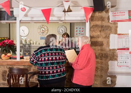 Sottoposto a embargo il 0001 martedì dicembre 18 USO EDITORIALE SOLO Postmistress Stella Robinson serve i clienti al Plough Inn nel villaggio di Marsh Gibbon, Aylesbury vale, Buckinghamshire. Il pub contiene una filiale dell'Ufficio postale, aperta da mezzogiorno alle 23.00 tra il martedì e la domenica, che lo rende la sosta perfetta per coloro che desiderano inviare carte e regali e godersi un po' di spirito natalizio allo stesso tempo. Foto Stock