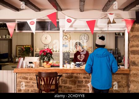 Embargo al 0001 Martedì Dicembre 18 USO EDITORIALE SOLO Postmistress Stella Robinson serve un cliente al Plough Inn nel villaggio di Marsh Gibbon, Aylesbury vale, Buckinghamshire. Il pub contiene una filiale dell'Ufficio postale, aperta da mezzogiorno alle 23.00 tra il martedì e la domenica, che lo rende la sosta perfetta per coloro che desiderano inviare carte e regali e godersi un po' di spirito natalizio allo stesso tempo. Foto Stock