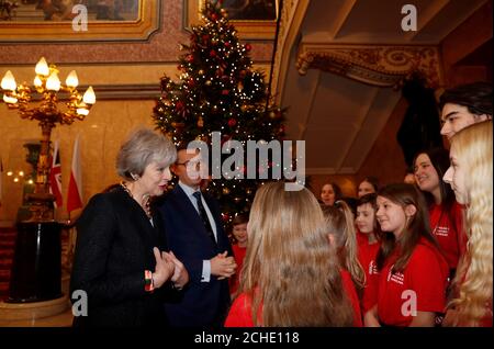 Il primo ministro Theresa May e il primo ministro polacco Mateusz Morawiecki parlano con i membri di un coro di bambini dopo aver cantato i canti durante le consultazioni intergovernative Regno Unito-Polonia a Lancaster House, Londra. Foto Stock