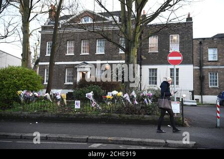 Una donna passa accanto a tributi floreali sulla scena di Forest Road, a est di Londra, dove una donna di 21 anni è morta dopo essere stata colpita da una macchina della polizia che risponde a una chiamata del 999. Foto Stock