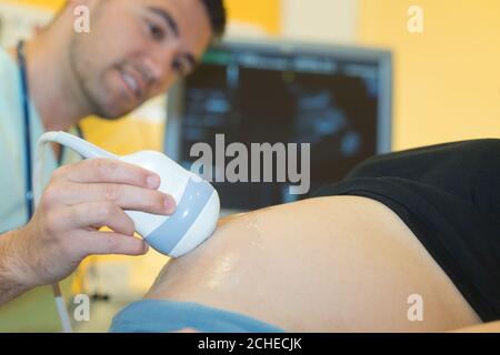 Primo piano dello scanner a ultrasuoni sul grumo della donna incinta Foto Stock