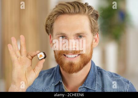 giovane uomo che tiene il sushi roll Foto Stock