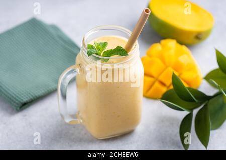 Gustoso frullato vegetariano di mango in un bicchiere con beva di bambù paglia Foto Stock