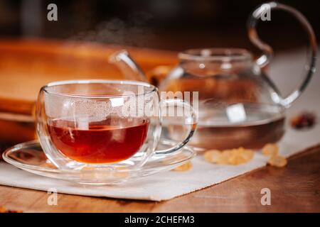 Tazza di tè caldo con zucchero di roccia, foglie di tè secco servite in tazza di tè termocass Foto Stock